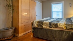 A bedroom with a bed, wooden wardrobe, and a potted plant. - Location! Value! Steps to Beach! Perfect for Summer Trip- Spacious 4-5BR Retreat (Hampton)