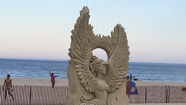 A sand sculpture of an angel with wings and a tail, located on a beach with a fence in the background. - Location! Value! Steps to Beach! Perfect for Summer Trip- Spacious 4-5BR Retreat (Hampton)
