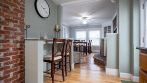A dining area with wooden chairs, a dining table, and a kitchen area with a refrigerator and stove. - Location! Value! Steps to Beach! Perfect for Summer Trip- Spacious 4-5BR Retreat (Hampton)
