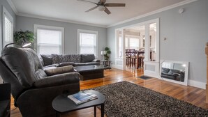 A modern living room with a leather sofa, a coffee table, and a rug. There is a dining area with a table and chairs. - Location! Value! Steps to Beach! Perfect for Summer Trip- Spacious 4-5BR Retreat (Hampton)