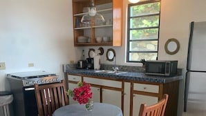 A kitchen with a dining table, chairs, a stove, a microwave, and a refrigerator.