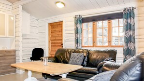A cozy room with a leather sofa, a wooden table, and a window with curtains. - Awesome home in Hemsedal with WiFi (Hemsedal)