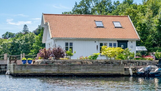 A house with a red-tiled roof, a dock, and boats.