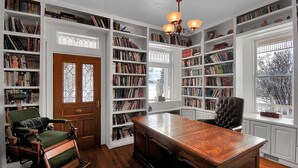 Eine Bibliothek mit Bücherregalen, einem Holztisch und zwei Stühlen.