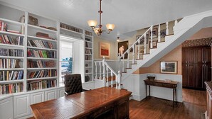 Eine geräumige Bibliothek mit Bücherregalen, einem Holztisch und einer Treppe.