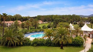 Un resort con piscina rodeada de palmeras y sillas de descanso.