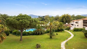 Un jardín exuberante con un sendero serpenteante, palmeras y una piscina al fondo.