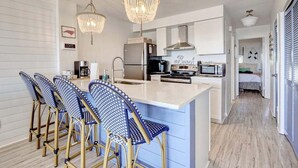 Une cuisine moderne avec un îlot central, des tabourets de bar et un lustre.