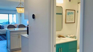 Une cuisine moderne avec un plan de travail blanc, un meuble de couleur turquoise et un luminaire suspendu.