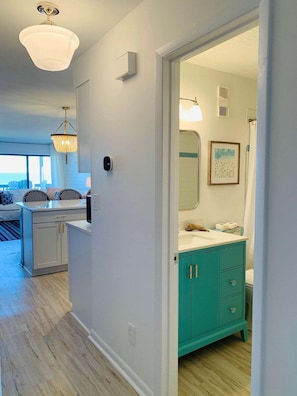 A modern kitchen with a white countertop, a teal cabinet, and a hanging light fixture. - Elevator. Oceanfront. Big Deck. Pool. (Carolina Beach)