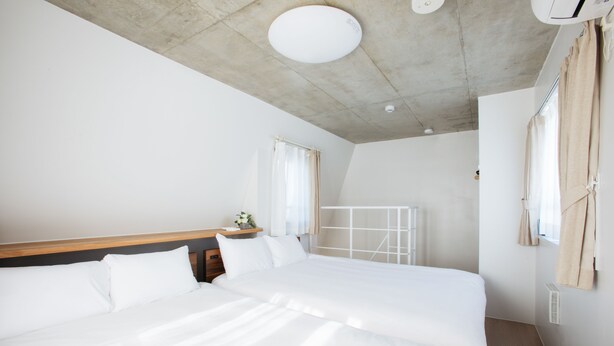 A modern hotel room with a large bed, wooden headboard, and a ceiling with a recessed light fixture. - Laffitte Tokyo WEST (Tokyo)