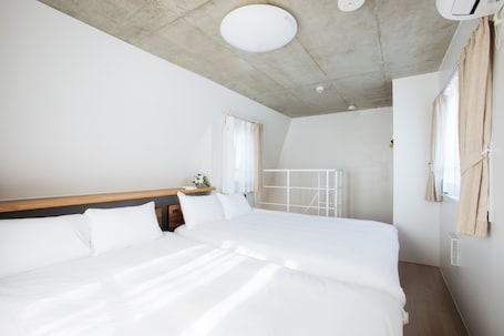A modern hotel room with a large bed, wooden headboard, and a ceiling with a recessed light fixture.