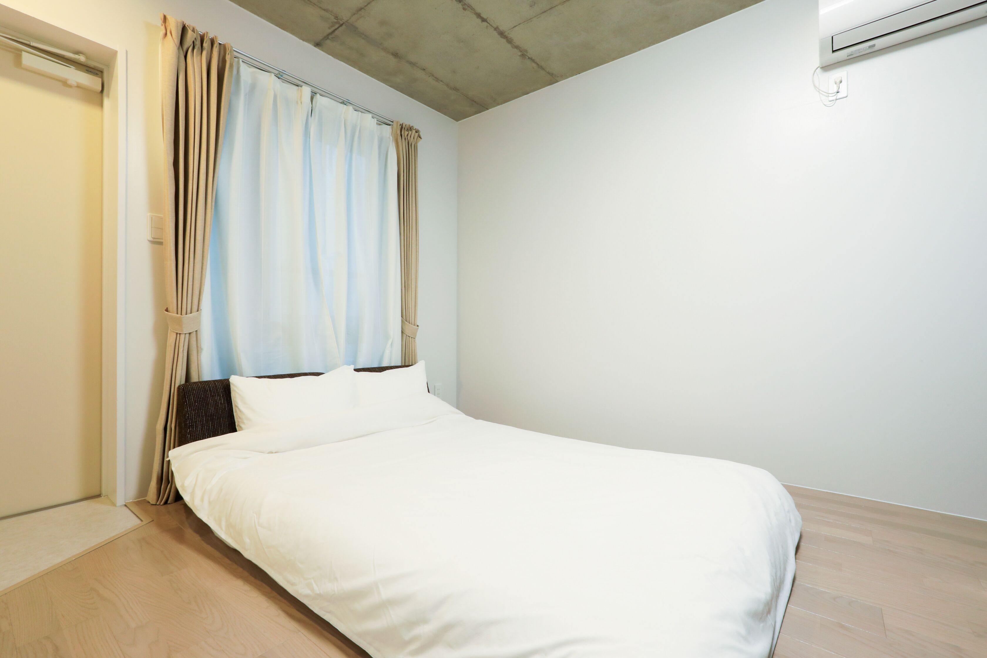A bedroom with a bed, curtains, and an air conditioning unit.