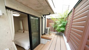 A compact room with a bed, a sliding glass door leading to a balcony, and an air conditioning unit. - Laffitte Tokyo WEST (Tokyo)