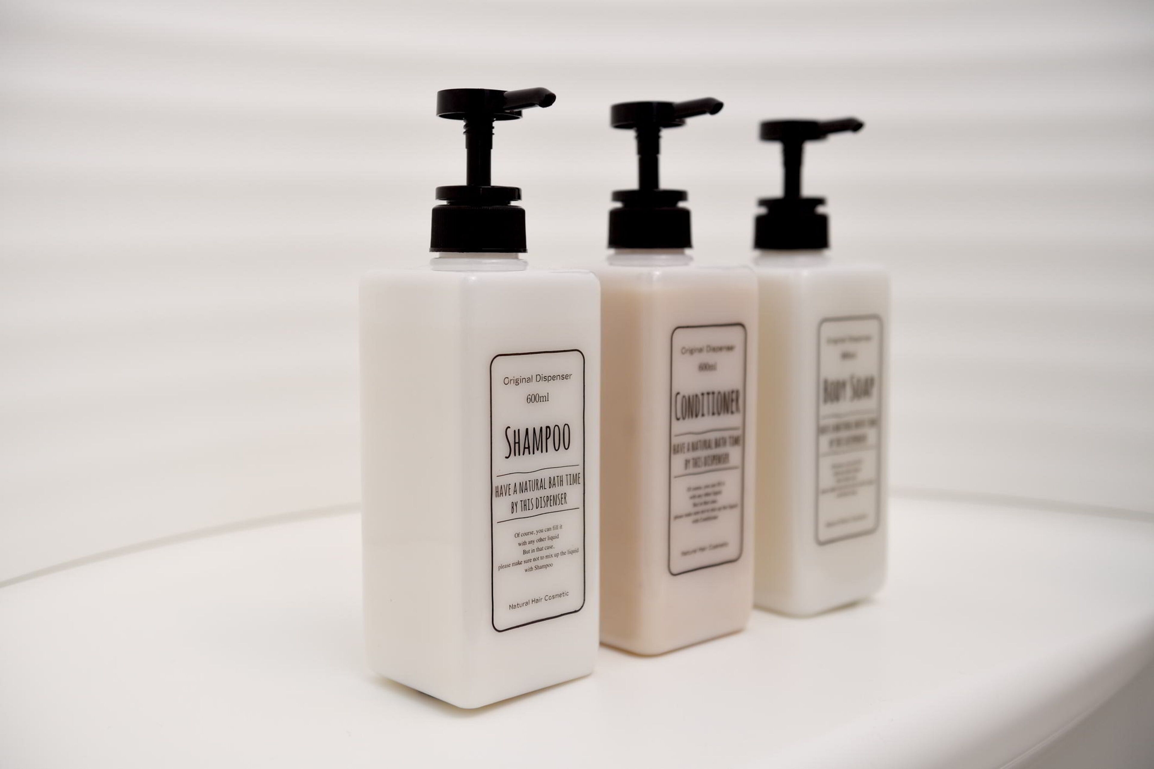 Three bottles of shampoo, conditioner, and body wash on a white surface.