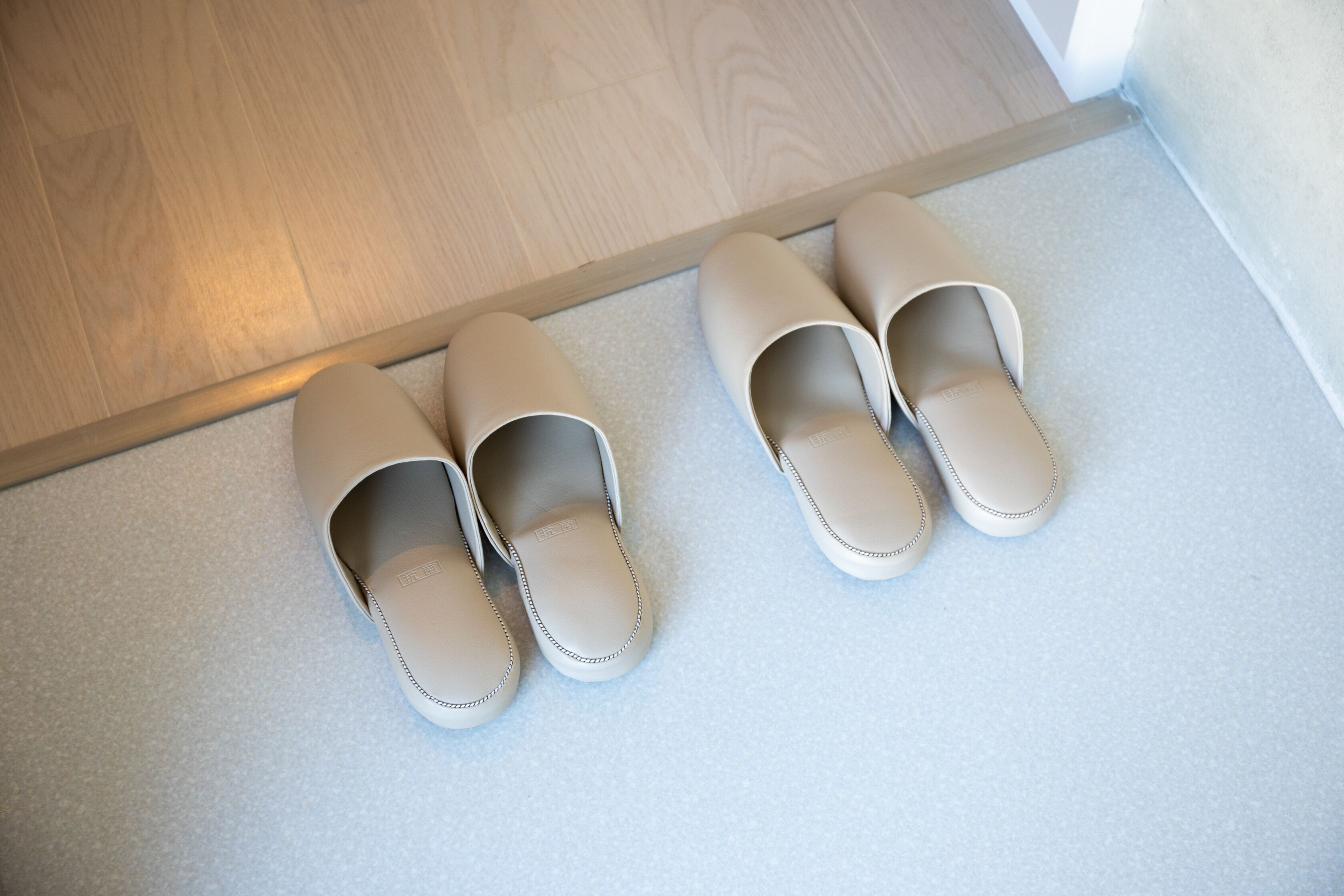 Une paire de pantoufles beiges sur un tapis de couleur claire.