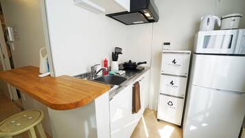 Cuina moderna amb taulell de fusta, rentamicroones d'acer inoxidable i nevera blanca amb dispensador d'aigua.