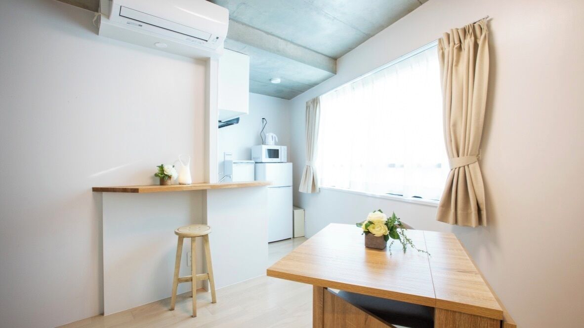 Une petite cuisine équipée d’un four à micro-ondes, d’une étagère et d’un tabouret.