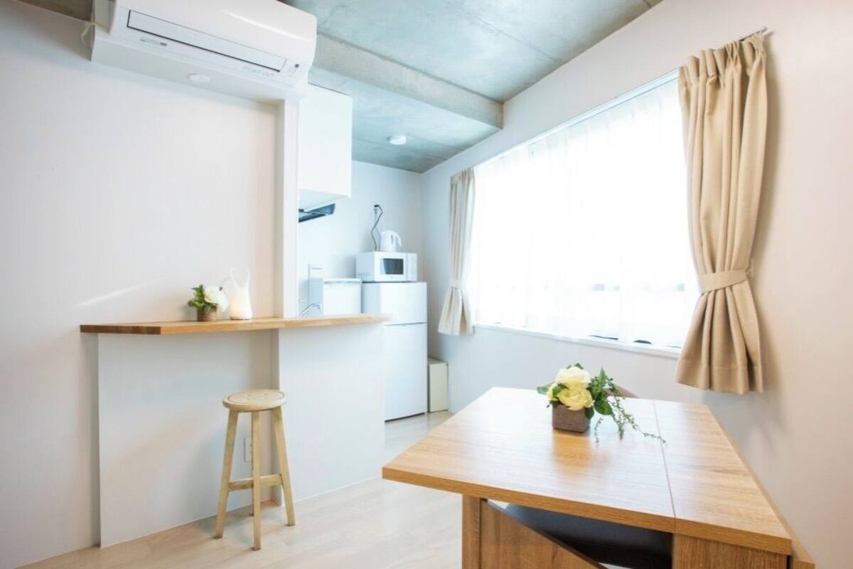 A small kitchenette with a microwave, a shelf, and a stool.