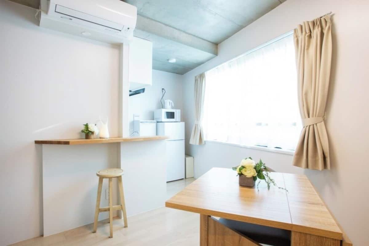 Une petite cuisine équipée d’un four à micro-ondes, d’une étagère et d’un tabouret.