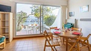 A dining area with a large sliding glass door leading to a balcony with a view of boats and greenery.