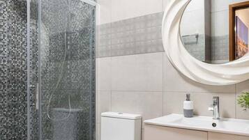 Ein modernes Badezimmer mit einer Duschkabine aus Glas, Toilette, Waschbecken mit Spiegel und Schrank.