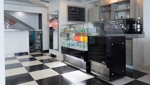 A modern café with a checkered floor, a refrigerated display case, and a coffee machine. - Hotel Aquarius (Barranquilla)