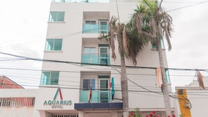 A multi-story hotel named 'Aquarius Hotel' with a modern facade, balconies, and a palm tree in front. - Hotel Aquarius (Barranquilla)
