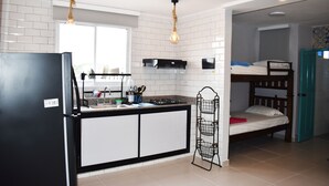A compact kitchen with a black refrigerator, white cabinets, and a window above the sink. - Hotel Aquarius (Barranquilla)