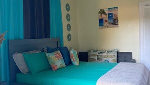A bedroom with a bed, curtains, a ceiling fan, a wall clock, and a beach-themed pillow. - MaryBo - Back Yard Oasis Studio (Nassau)