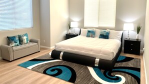 Une chambre à coucher comprenant un lit, deux tables de chevet, une commode, un canapé et un ventilateur de plafond.
