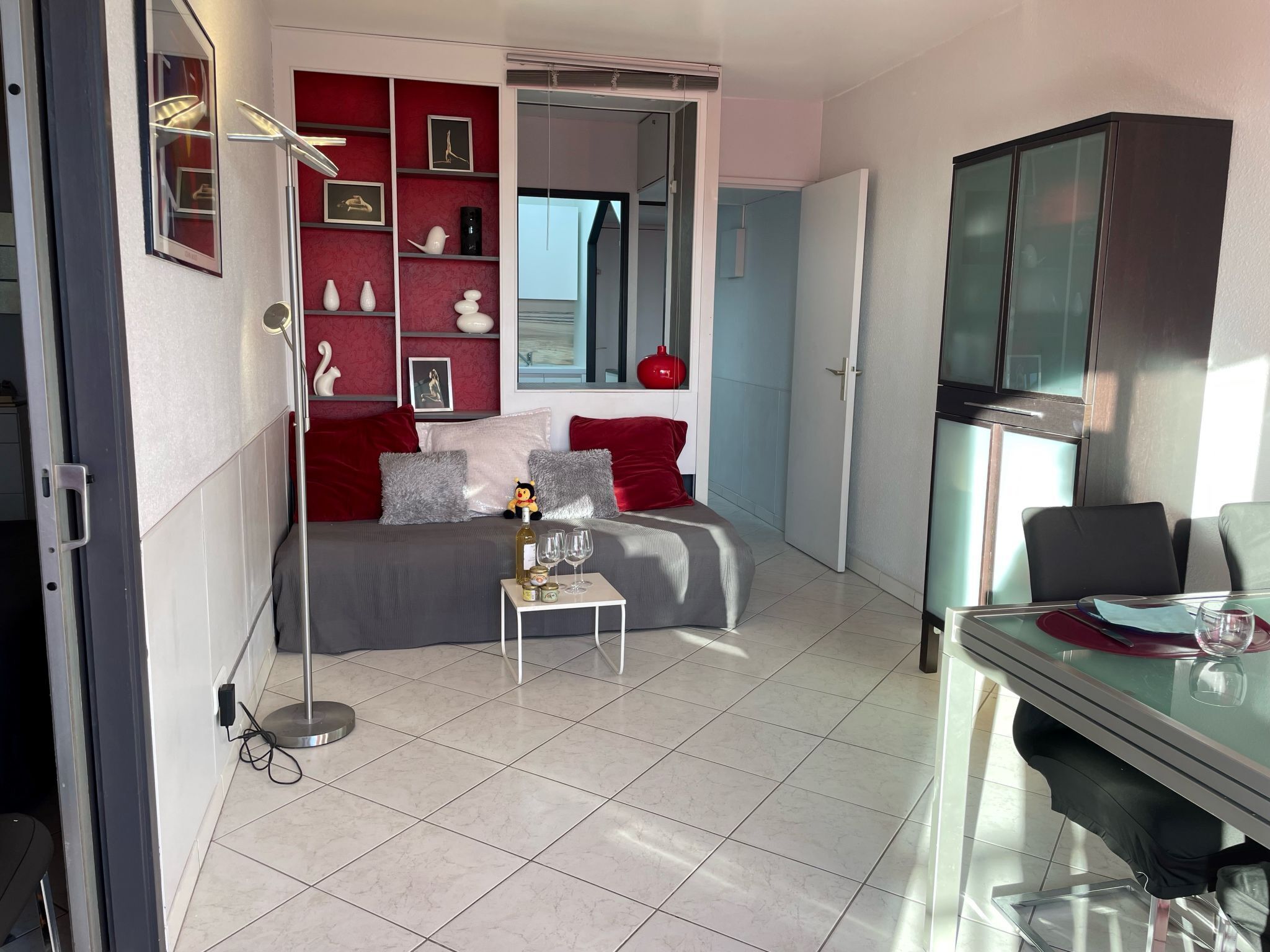 Una sala de estar moderna con un sofá, una mesita con bebidas y una zona de comedor con una mesa de vidrio.