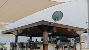 Een buitengebied met een bar, een schotelantenne, overdekte zitplaatsen en een toonbank.
