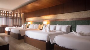 Een hotelkamer met drie bedden, houten hoofdborden en een houten vloer.