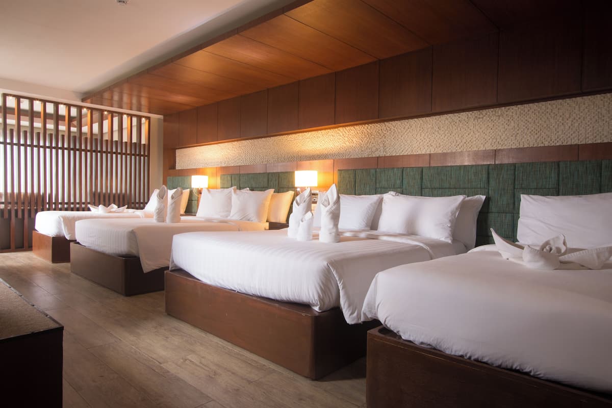 Une chambre d’hôtel avec trois lits, des têtes de lit en bois et un plancher en bois.