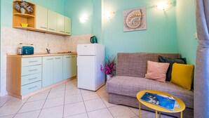 A compact living space with a kitchenette, a sofa, and a small table. - Apartments Vodnica - One-Bedroom Apartment with Balcony and Partial Sea View (Zaton Mali)