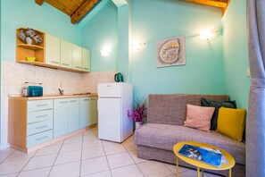A compact living space with a kitchenette, a sofa, and a small table.
