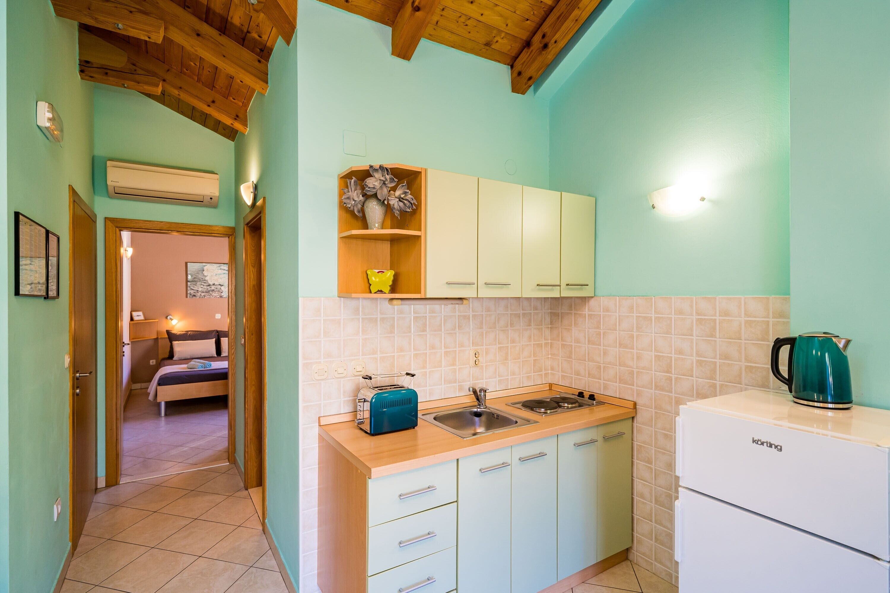Eine kleine Küche mit Holzbalkendecke, Spüle, Toaster und Kühlschrank.
