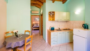 A cozy kitchen with wooden beams, a dining table with chairs, and a kitchenette. - Apartments Vodnica - One-Bedroom Apartment with Balcony and Partial Sea View (Zaton Mali)