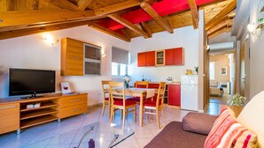 Un soggiorno moderno con una TV a schermo piatto, mobili in legno e un divano rosso.
