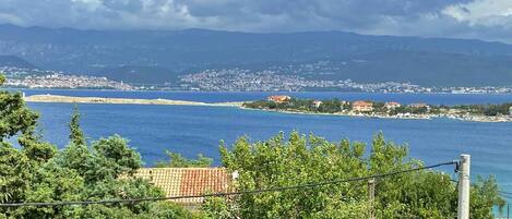 A coastal view with a clear sky, a body of water, and distant buildings.