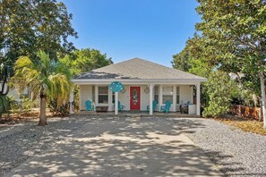 A single-story house with a red door, a porch with blue chairs, and a gravel driveway. - Private Heated Spa/Pool, 4min Walk To Beach, Pet Friendly, Zula Breeze Destin (Destin)