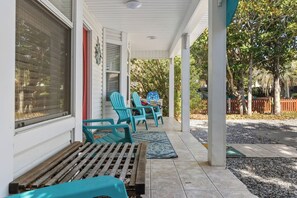 A covered porch with a bench, two chairs, and a small table. - Private Heated Spa/Pool, 4min Walk To Beach, Pet Friendly, Zula Breeze Destin (Destin)