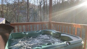 Ein Whirlpool auf einer Holzterrasse mit Blick auf Bäume im Hintergrund.