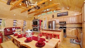 Ein Holzblockhaus-Interieur mit Essbereich, Küche und Wohnzimmer.