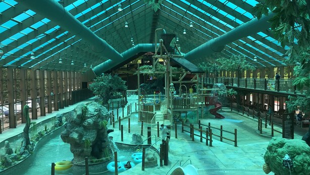 Ein großer Indoor-Wasserpark mit Rutschen, Luftmatratzen und einem Spielbereich.