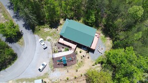 An aerial view of a building with a green roof, surrounded by trees. There are two cars parked in front. - Daydream Hideaway Cabin - Mtn retreat in the swaying pines, firepit, playground (Pigeon Forge)