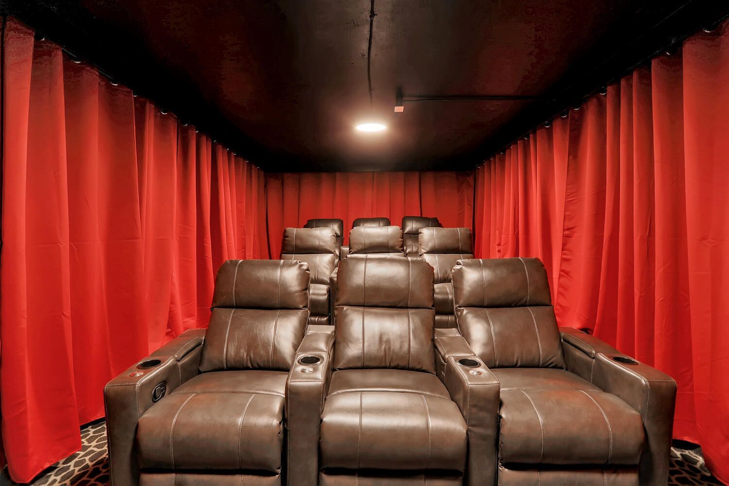 Un teatro con file di poltrone in pelle marrone e tende rosse.