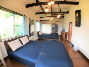 Quarto com duas camas, uma estante de livros, um relógio e uma janela com cortinas.