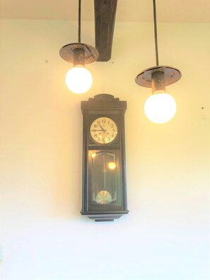 Eine an der Wand befestigte Pendeluhr, umgeben von drei hängenden, kugelförmigen Leuchten.